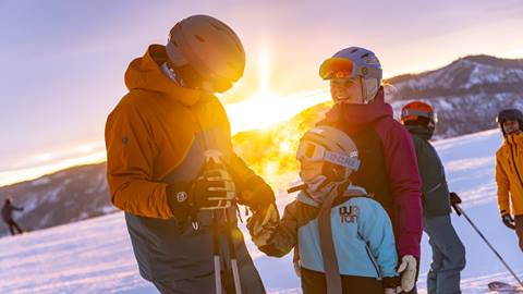 family of three skiing at sunset