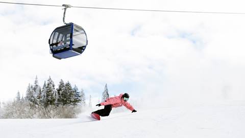A snowboarder going down a groomed trail.