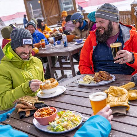 two males eating and drinking on mountain.