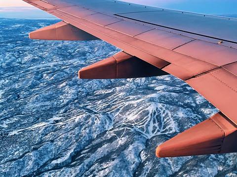 an airplane going over snow covered mountains